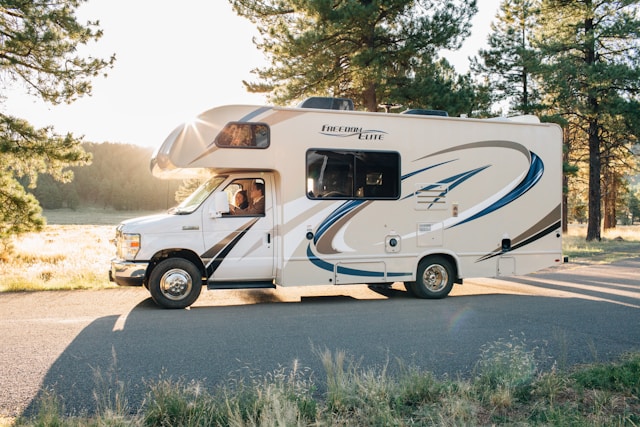Autocaravana perfilada estacionada frente a una playa de Huelva al atardecer.
