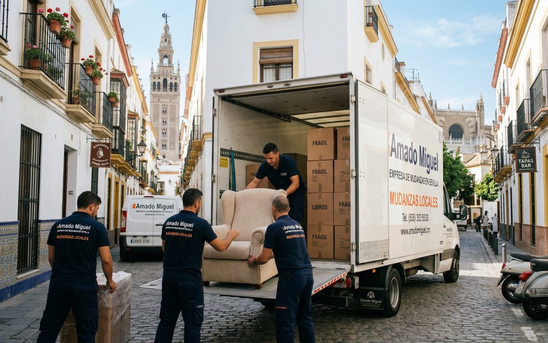 Operarios especializados de una empresa de mudanzas en Sevilla cargando cajas y muebles protegidos en un camión capitoné en una calle céntrica.